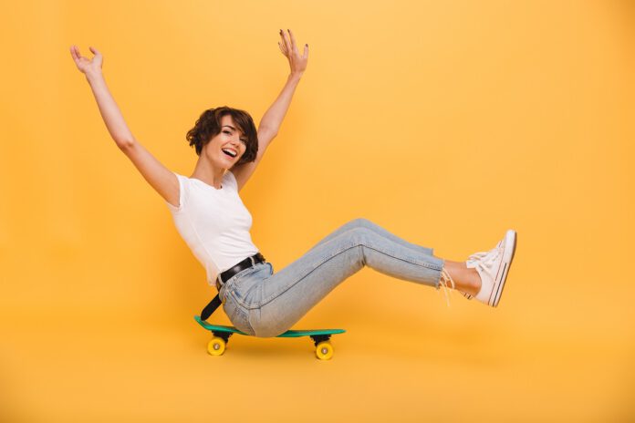 Portrait of a happy cheerful girl sitting on a skateboard