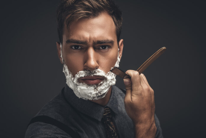 man shaving with straight razor